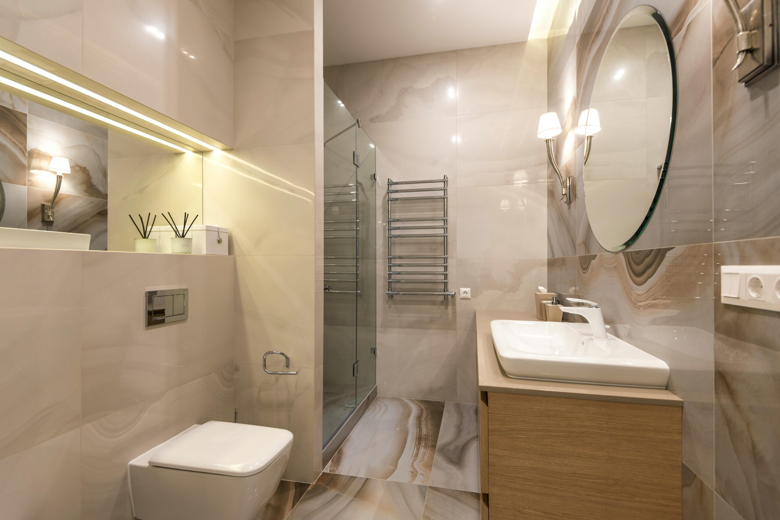 Elegant bathroom with marble tiles, large mirror, and modern fixtures.